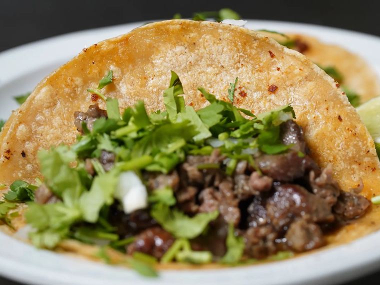 A steak taco on a corn tortilla with cilantro and onion.