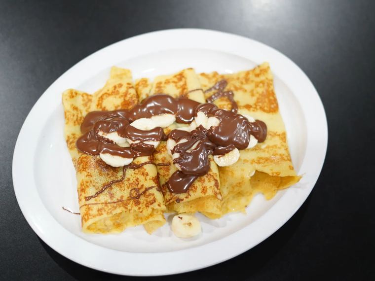 Crepes with Nutella and sliced banana on a white plate.