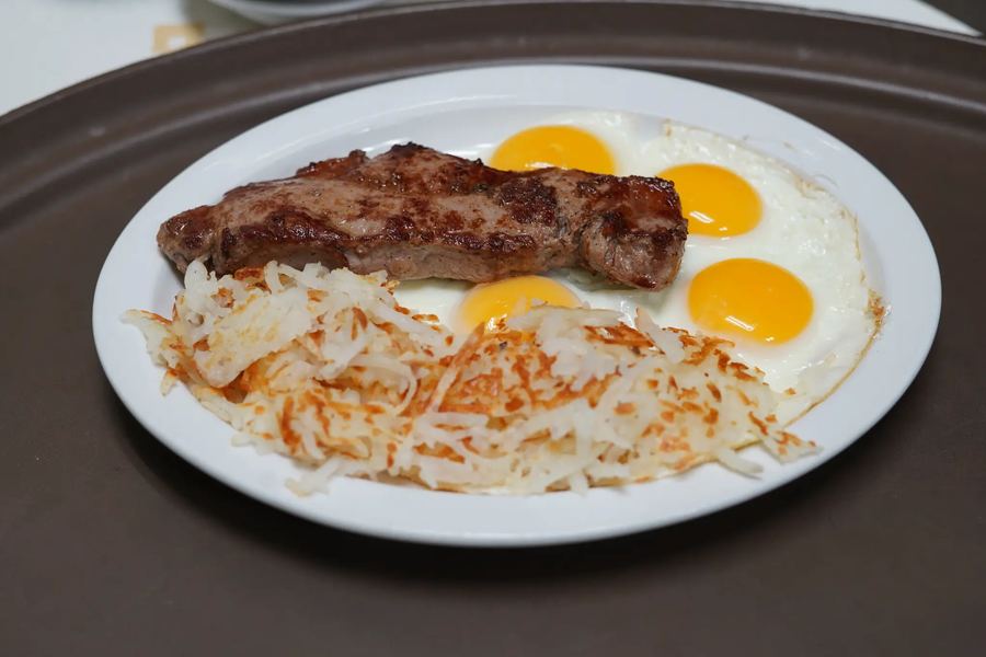 New York steak with two eggs and hash browns on a plate.