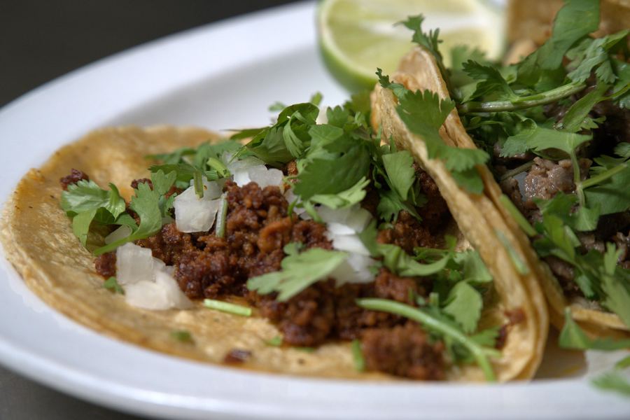 Chorizo tacos on corn tortillas topped with cilantro and diced onion.